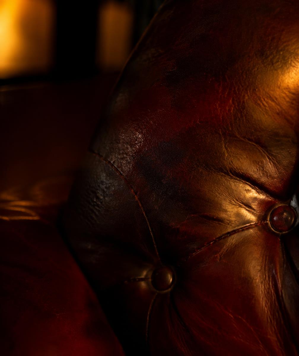 Aged oxblood leather chair in low amber light